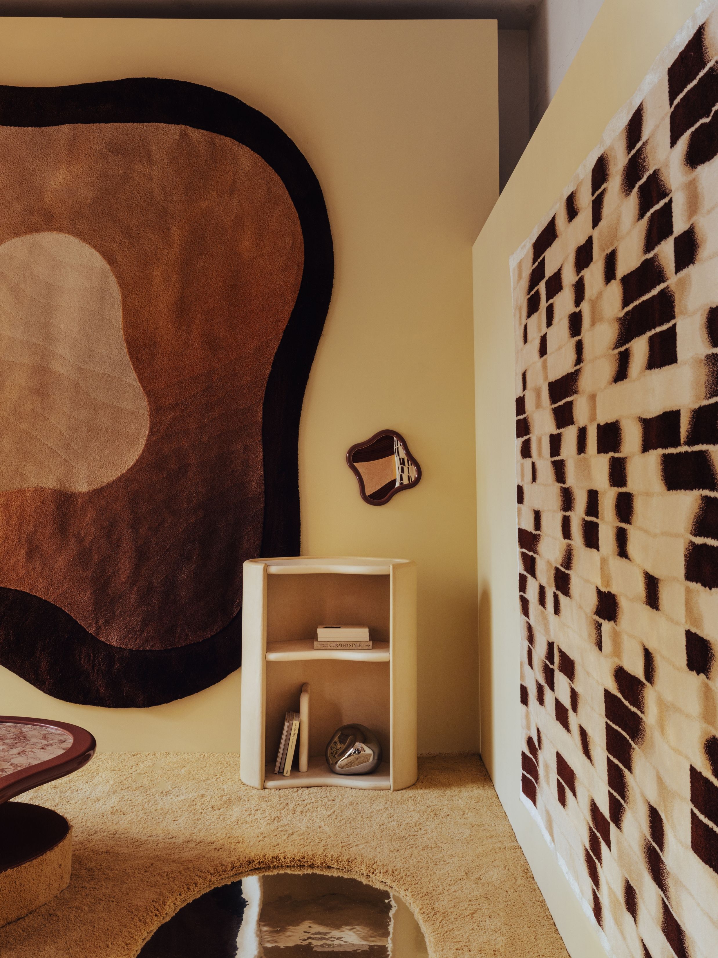 a showroom with neutral rugs on the wall, curvy furniture, and a mirrored and carpeted floor