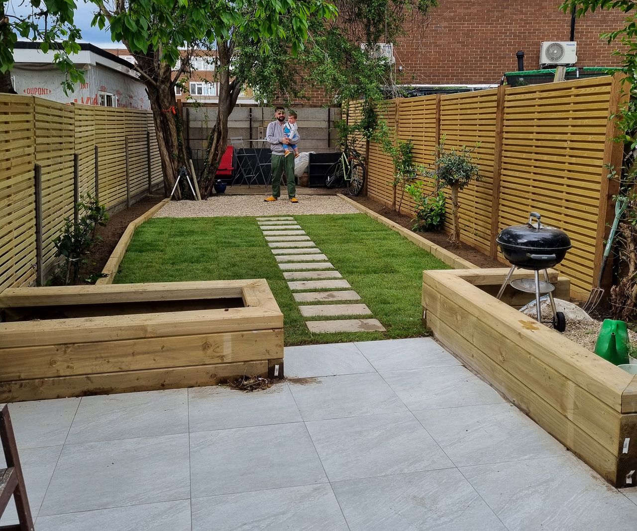A shot of a garden with raised beds, a pathway and freshly laid turf