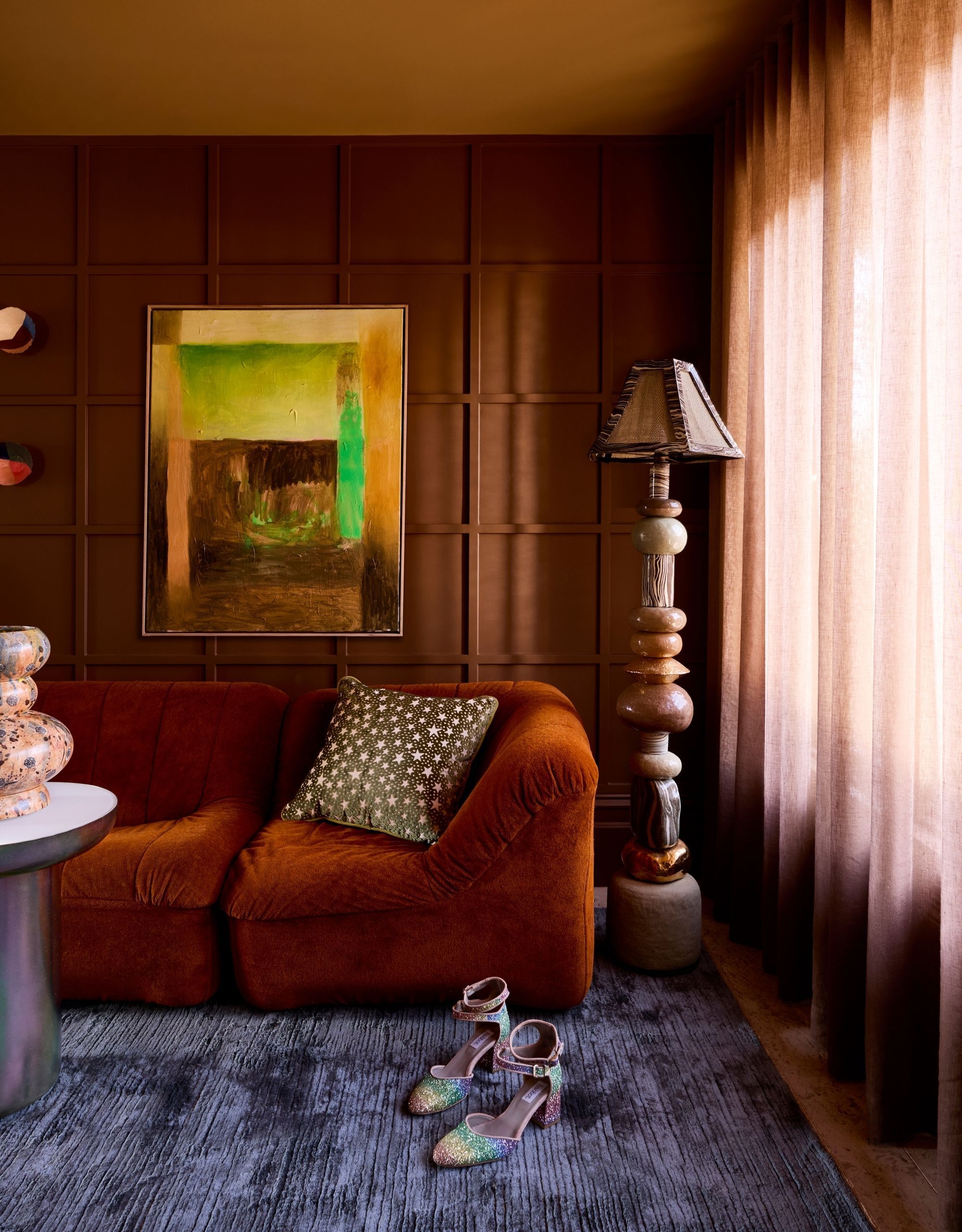 A living room with ochre ceilings, a red sofa, brown walls, and a deep blue rug. 