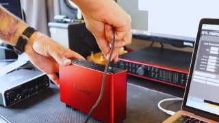 A man places a USB-C cable into an audio interface