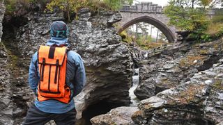 Man wearing a Mission Workshop Hauser 10L hydration pack looking at rustic bridge