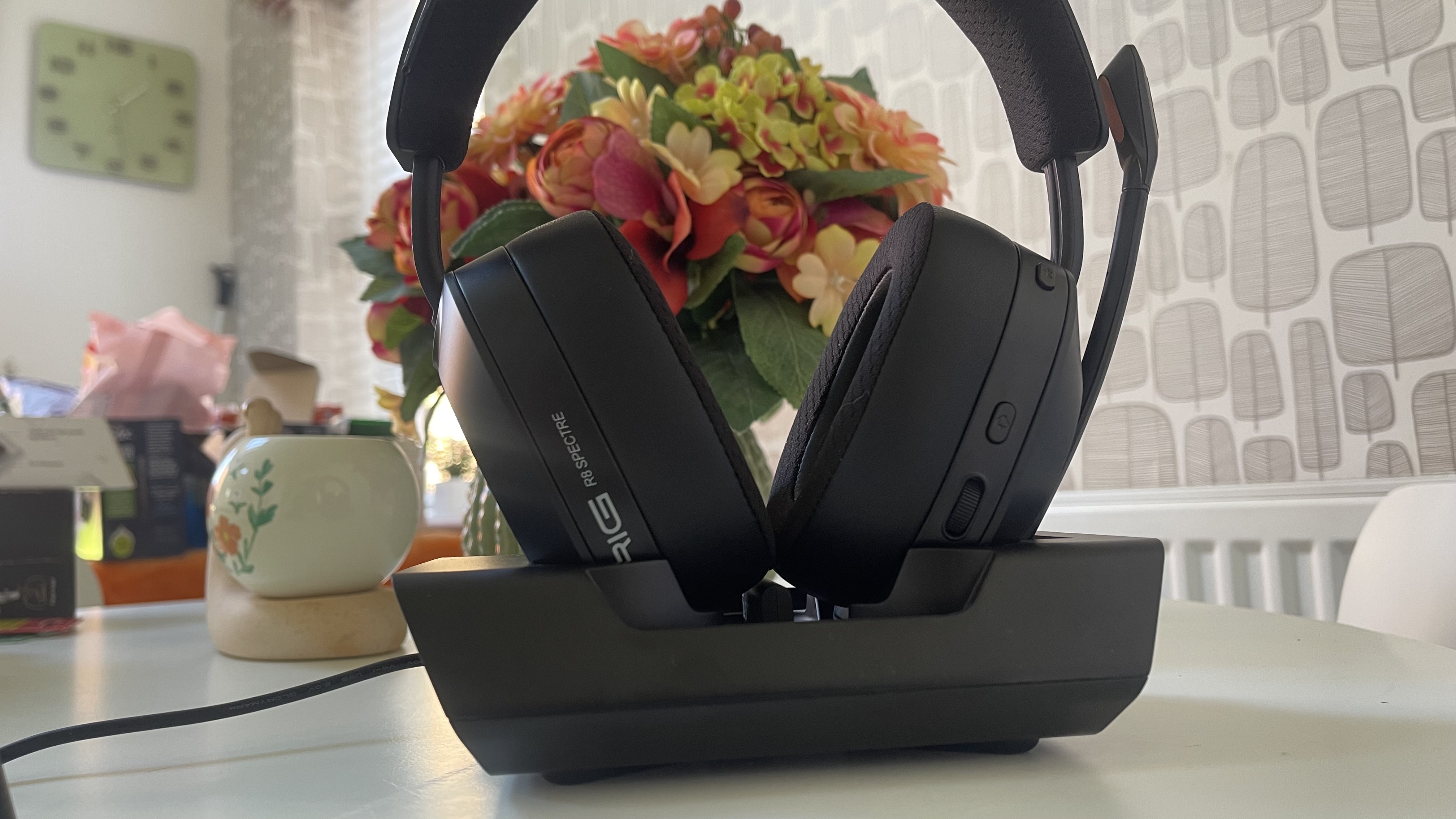 The RIG R8 PRO HS gaming headset on its base station sitting on a light coloured table