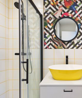 what is bauhaus style, small bathroom with bold wallpaper, yellow basin, square white tiles with yellow grout, black fixtures and fittings
