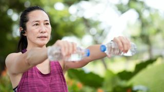 A woman uses water bottles as weights