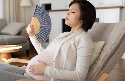 Woman using a fan while experiencing hot flashes in pregnancy