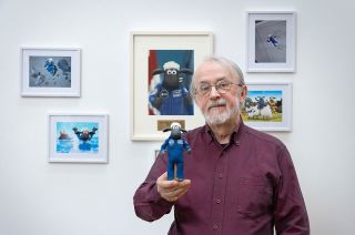 Peter Lord, co-founder and creative director at Aardman, holds up the stop motion animation figure of Shaun the Sheep that flew on NASA's Artemis 1 mission to the moon. Behind him is Shaun's European Space Agency astronaut portrait.