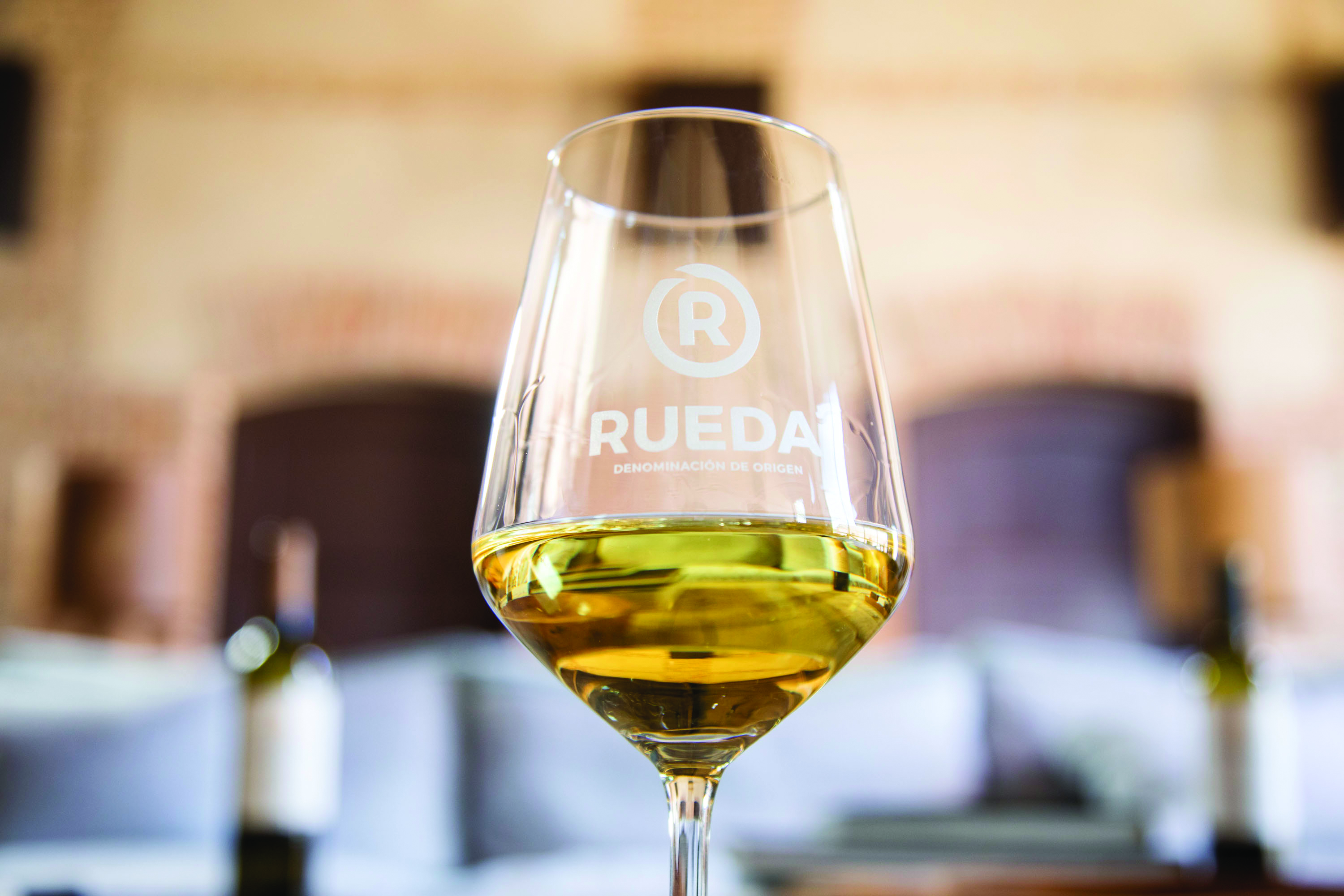 Close-up shot of glass of white wine with the DO Rueda logo on it