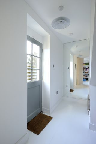 Hallway with a mirror and back door by Brown Architects