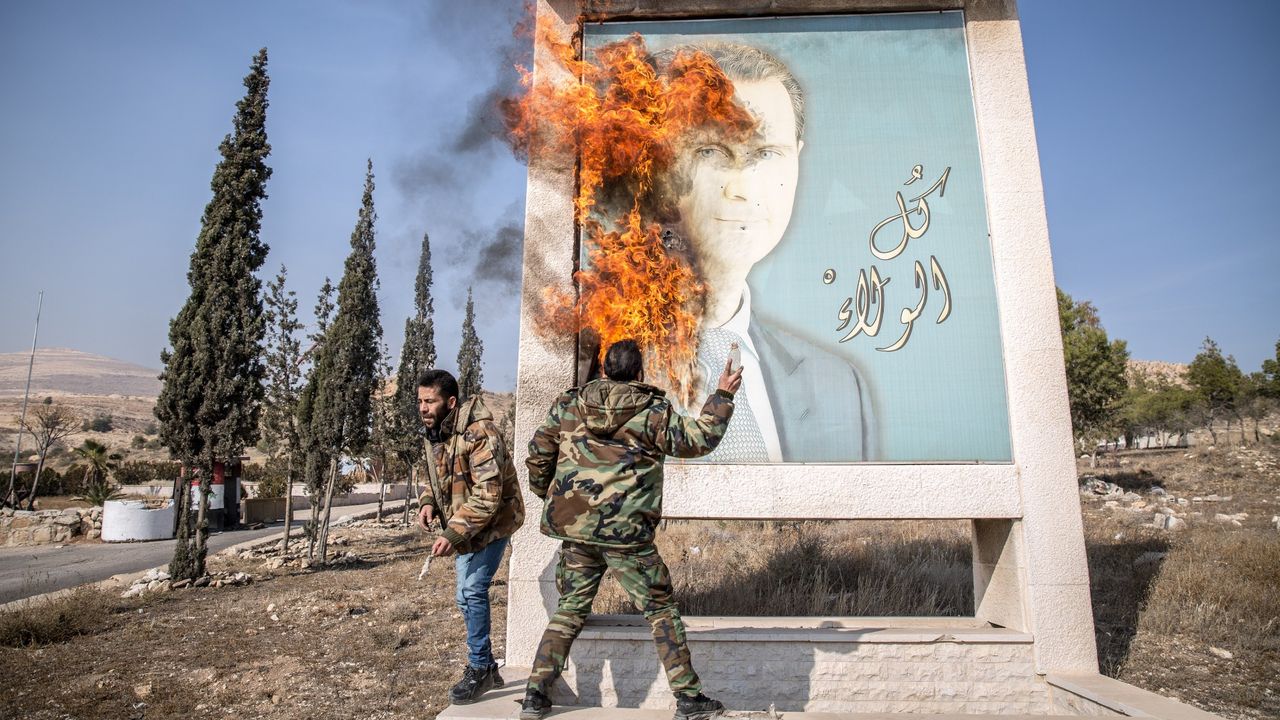 Fighters burn a picture of Bashar al-Assad close to Syria&#039;s border with Lebanon