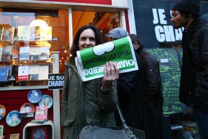 A woman holding the "survivor's edition" of Charlie Hebdo