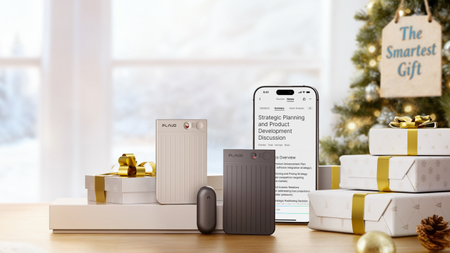 3 Plaud AI Notetakers placed beside Christmas gifts, in front of a Christmas Tree