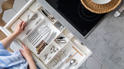 An open white drawer in a kitchen with organizers