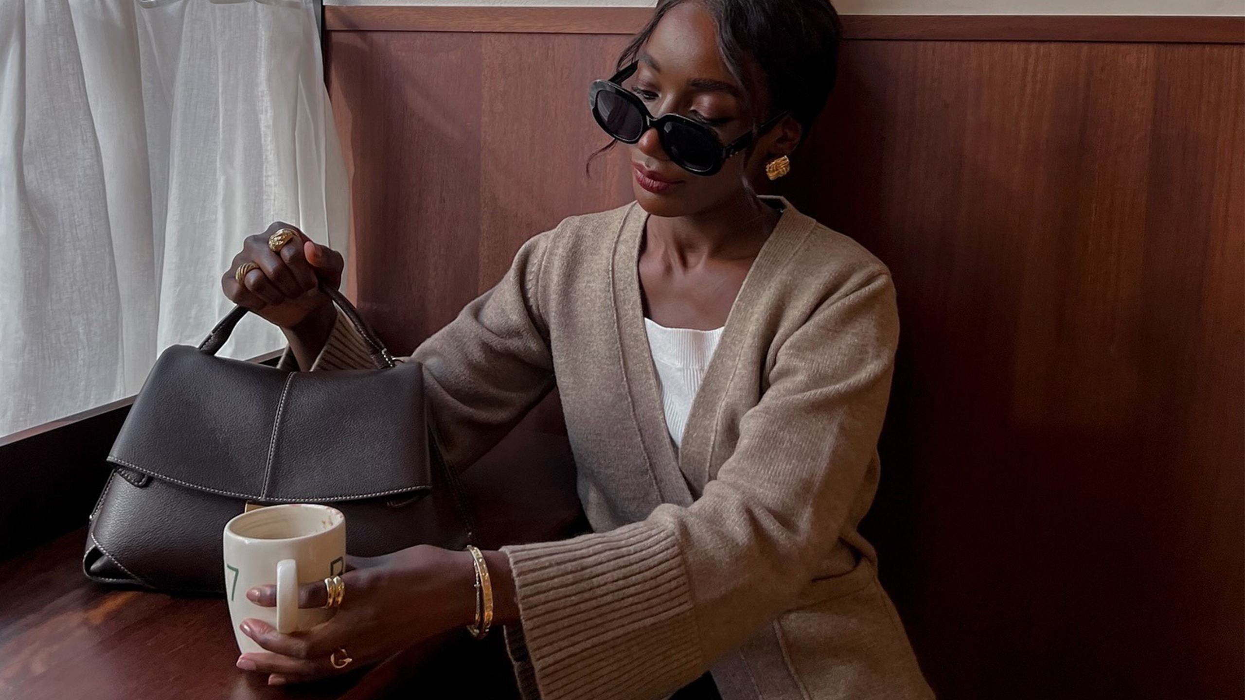 Aida Badji wearing cardigan and oversize sunglasses.