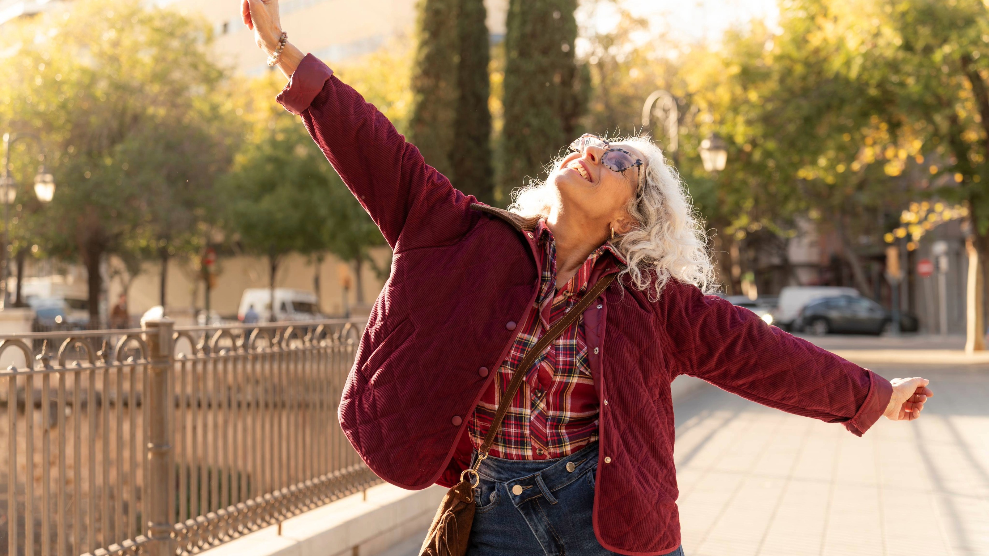 Senior woman standing with arms open wide and smiling, enjoying freedom