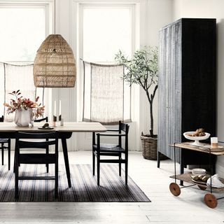 A white modern dining room with woven pendant over dining table and serving trolley