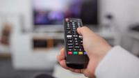 Watching TV and using remote controller. Hand with remote controller changing channels or opening apps on smart tv