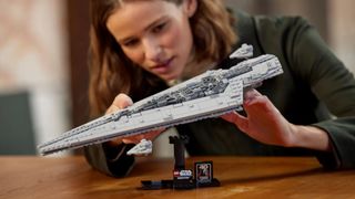 The Lego Executor Super Star Destroyer set on its stand on a wooden table, being posed by a woman
