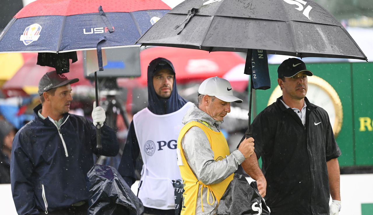 DeChambeau and Koepka with their caddies under an umbrella