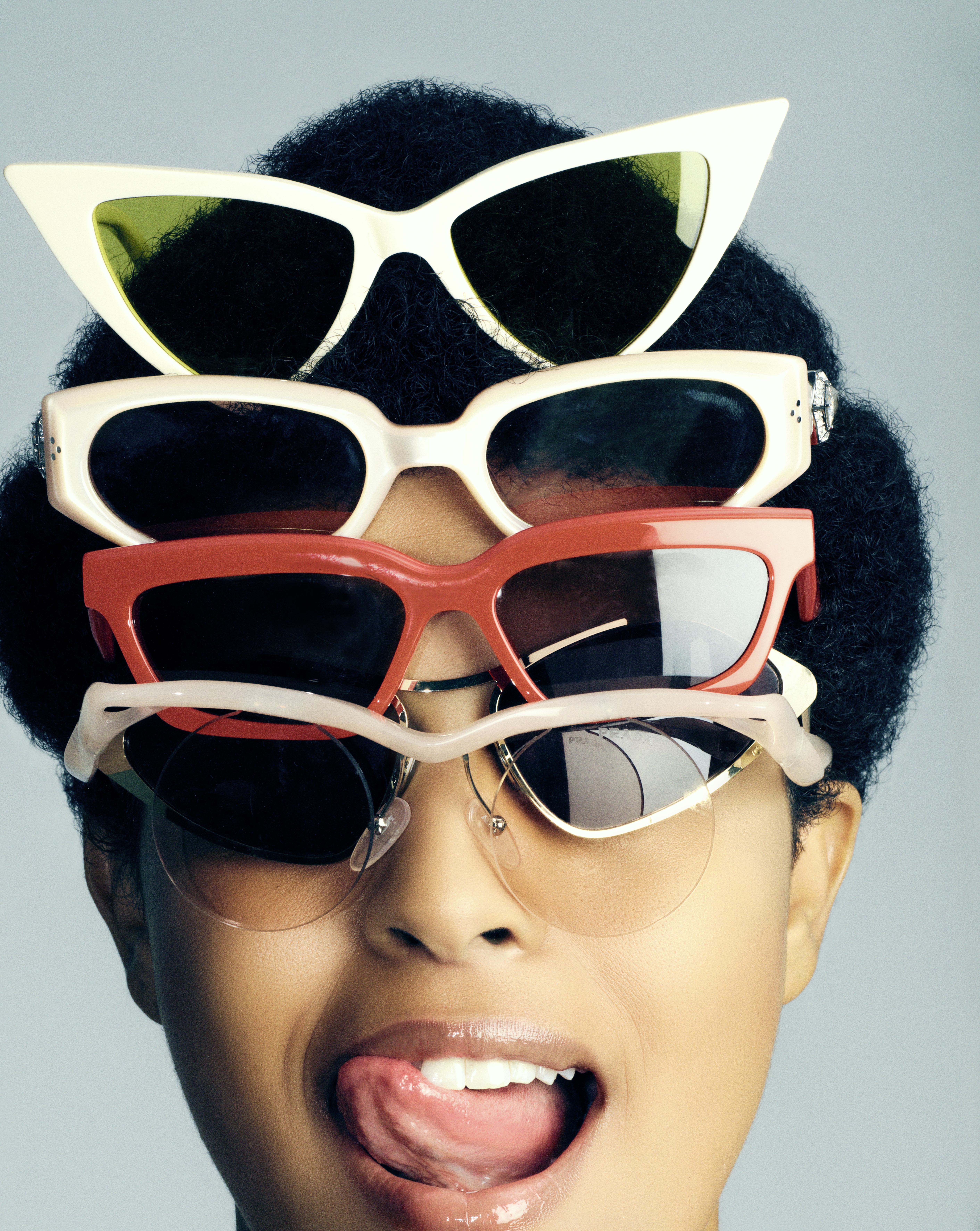 Model posing with five sunglasses stacked on her head