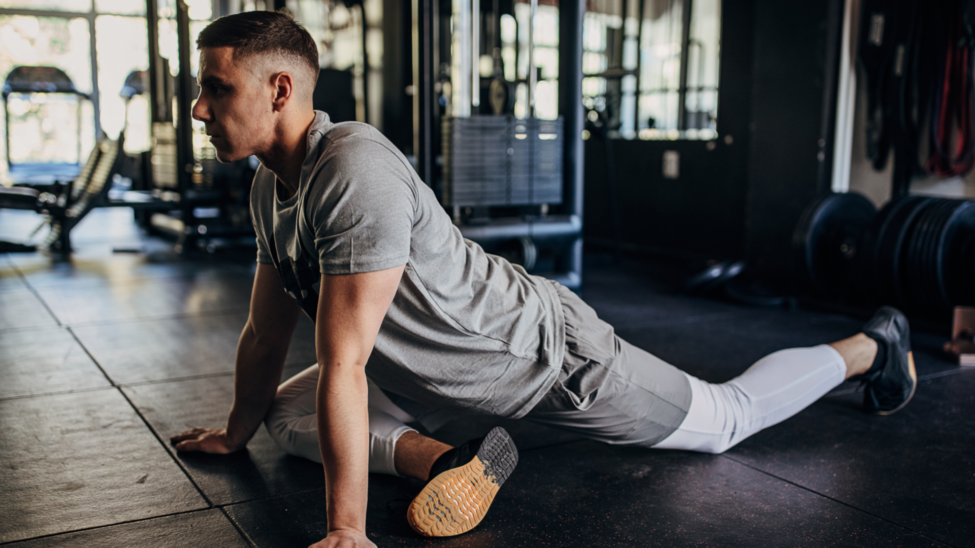 A man performing the pigeon pose at the gym