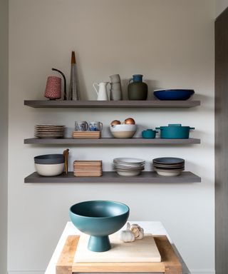 Minimalistic open wall shelving holding crockery in a kitchen