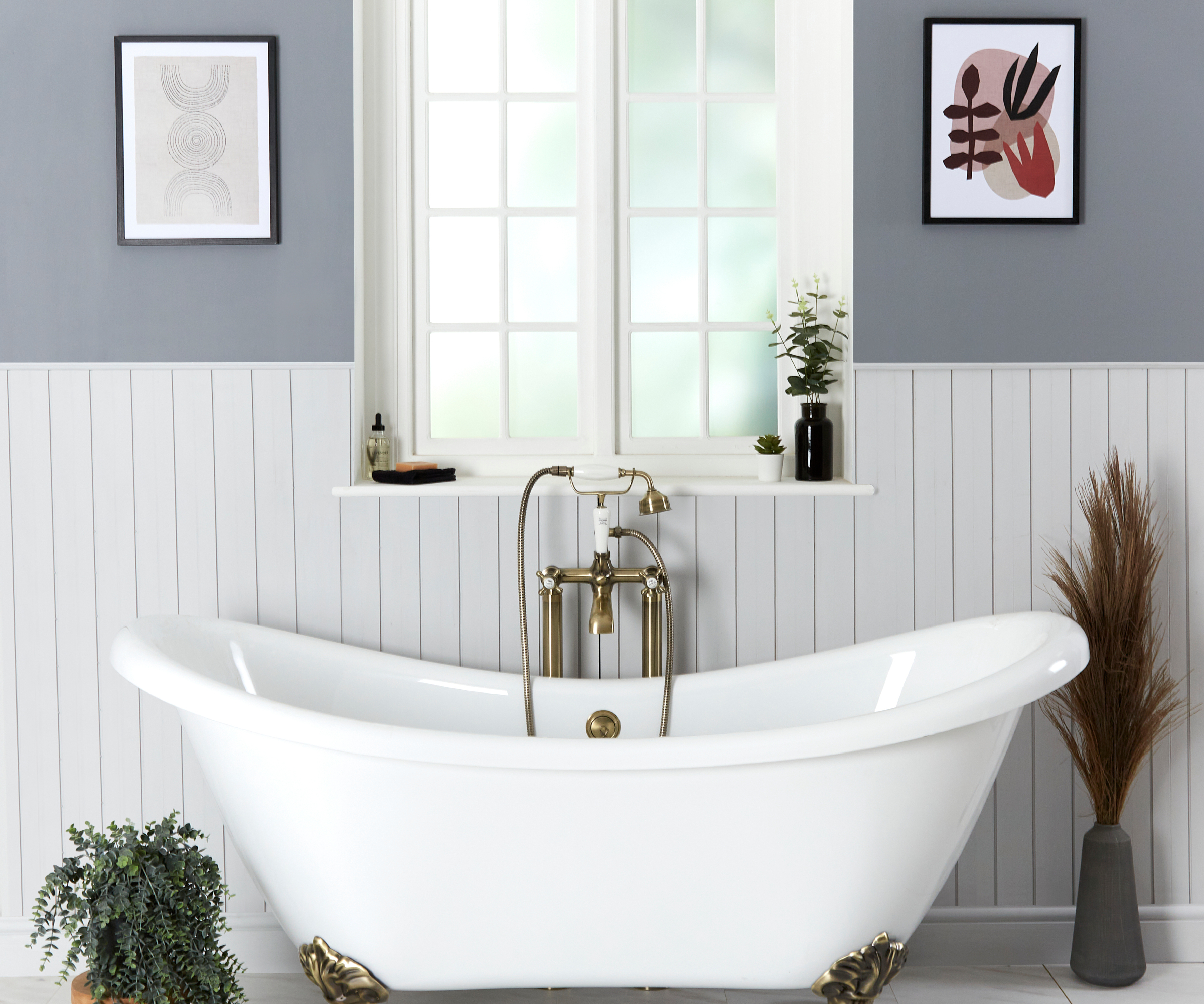 bathroom with white panelled walls, grey paint above, framed artwork on walls, and window with white freestanding bath below