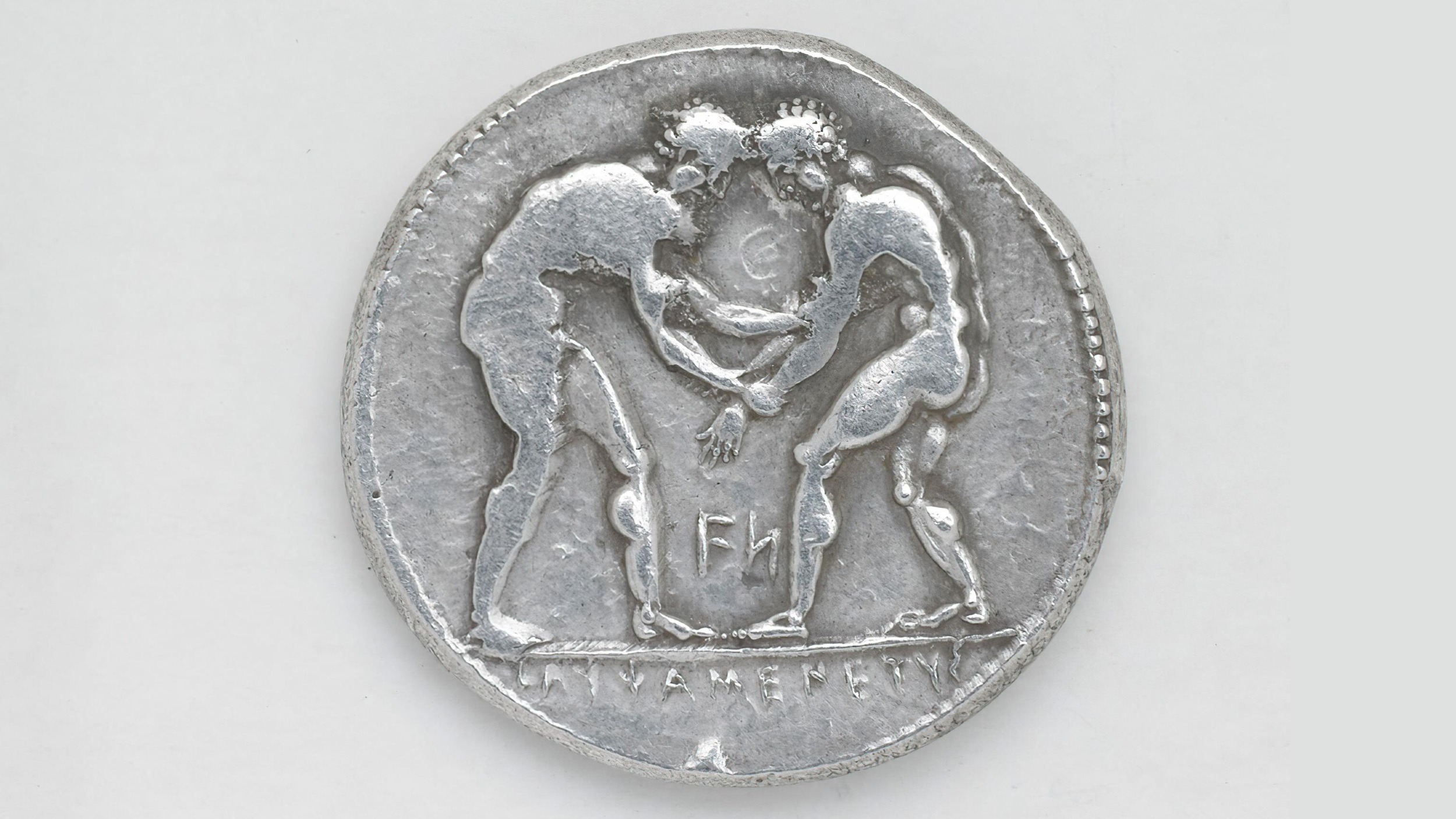an ancient silver coin depicting two male wrestlers