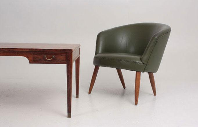 A traditional dark wooden office desk with a green leather tub chair.