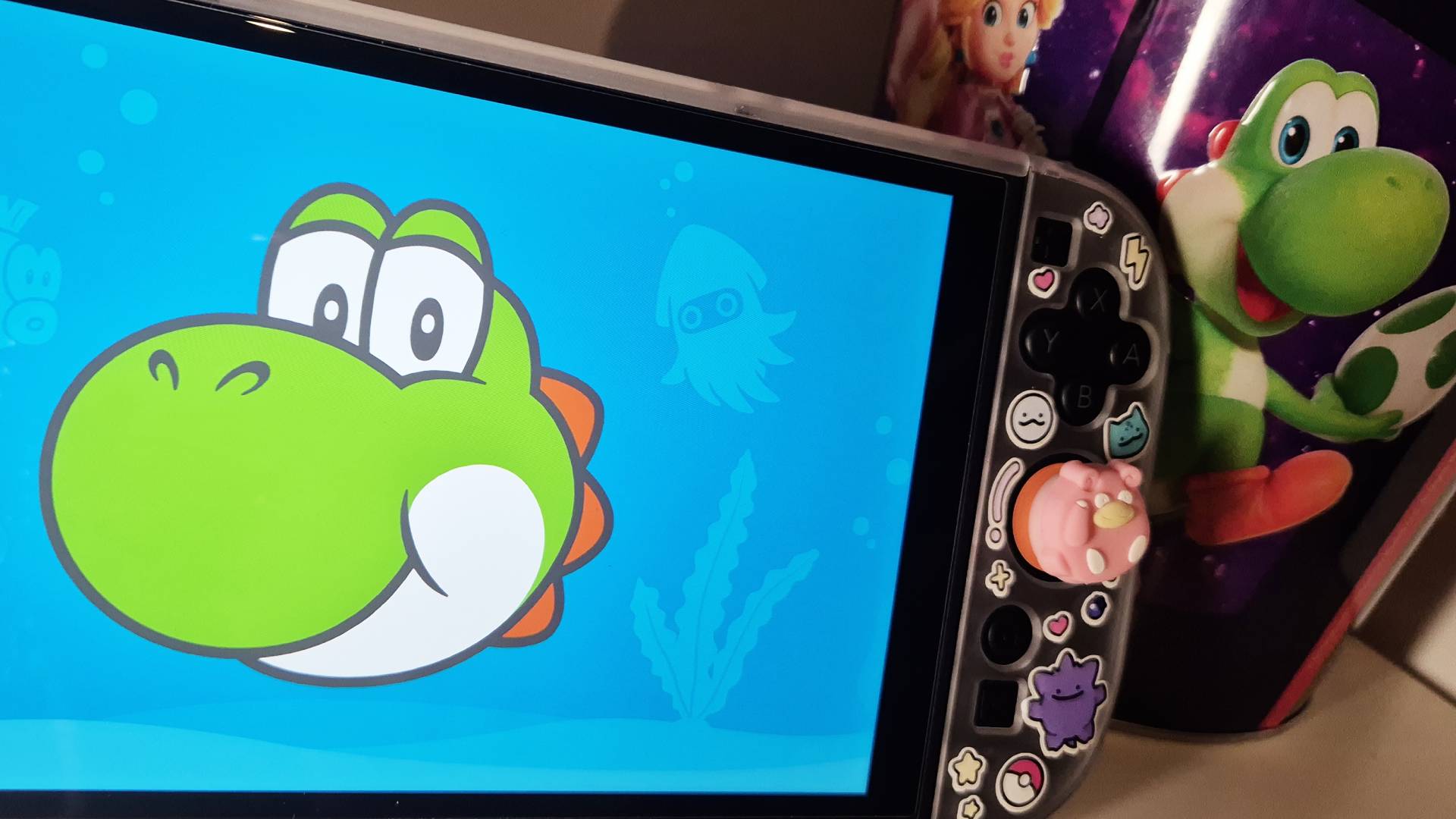 Photo of Hello, Yoshi! running ona a Switch 2 with a Yoshi popcorn bucket sitting to its side.