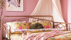 Try easy small bedroom upgrades for beautiful effect such as this dusky pink bedroom with a yoga wall art print, a lamp with white drapes, and a rose gold bed with yellow bedding, a pink throw, and green circular throw pillow