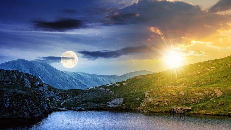 Worm moon—day and night time change concept above summer landscape with lake on high altitude. beautiful scenery of fagaras mountain ridge. open view in to the distant peak beneath a clouds with sun and moon