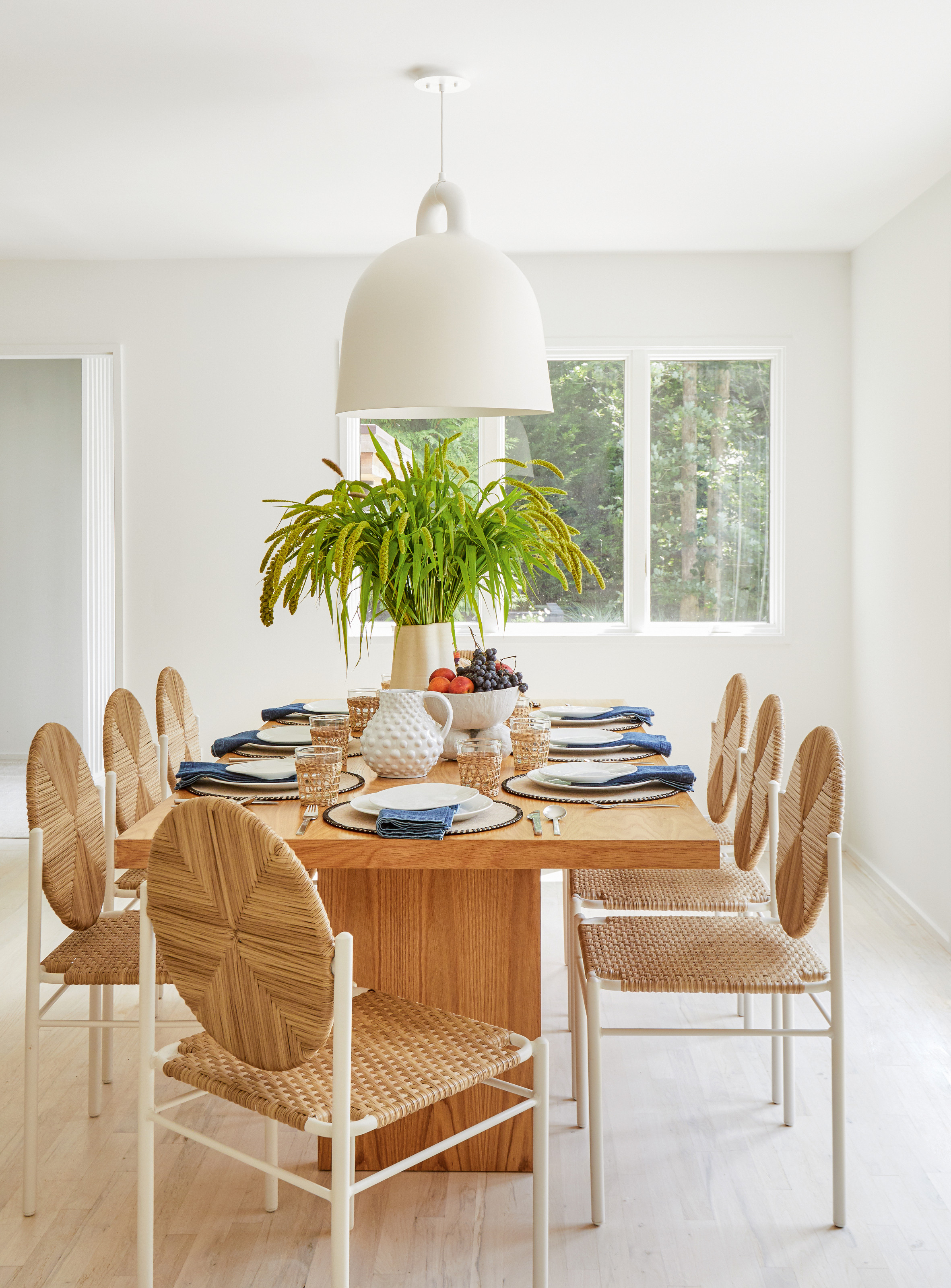 Dining room with wood table, woven chairs and white oversized pendant light