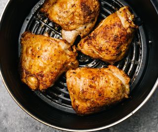 An air fryer basket with freshly cooked chicken