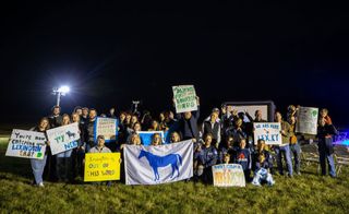 a crowd of people holding signs at night in a grassy field.
