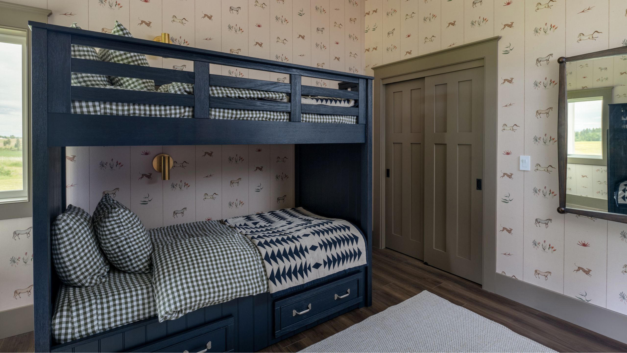 a wallpapered playful bunk room with navy bunks and gingham bedding