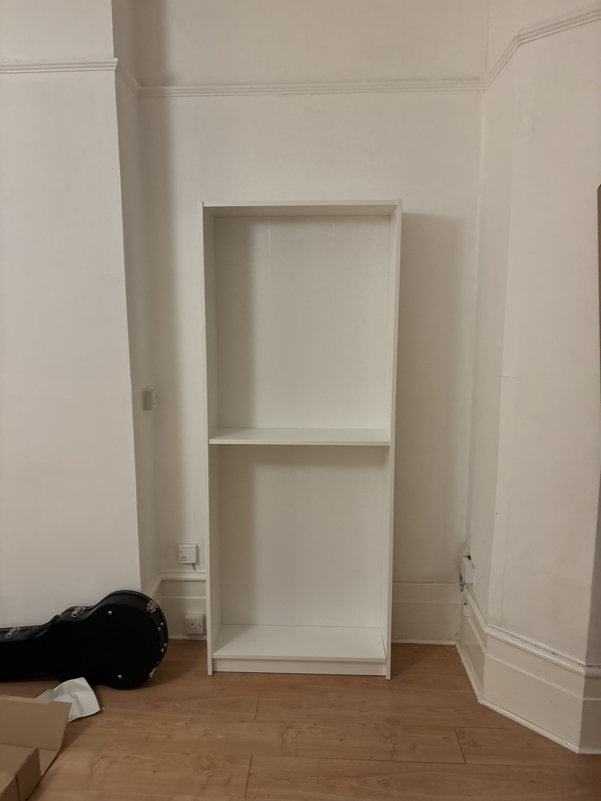 Image of a plain IKEA Billy bookcase in a white living room with high ceilings and wooden flooring.