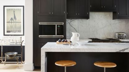 black kitchen with white marble backsplash and island