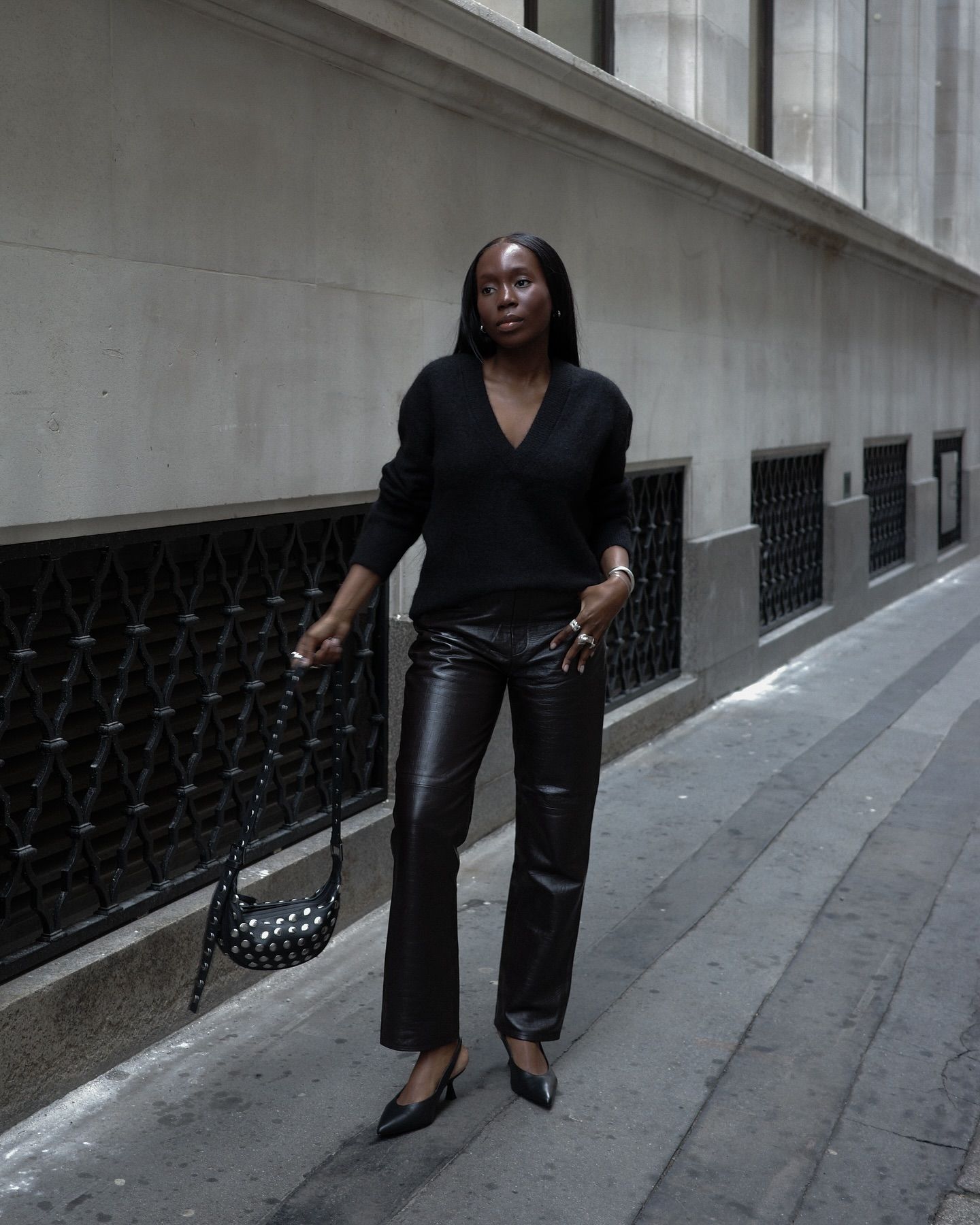 Danielle wears leather pants, a black sweater, and black slingbacks.