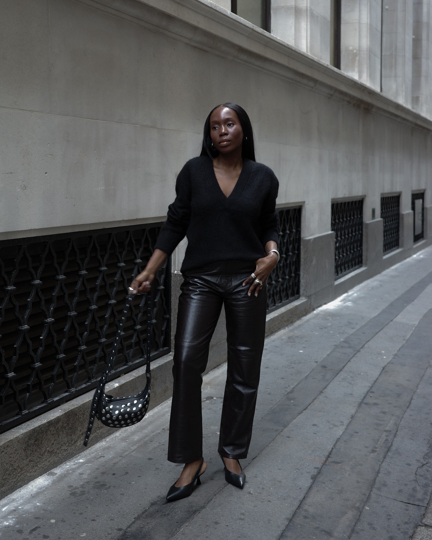 Danielle wears leather pants, a black sweater, and black slingbacks.