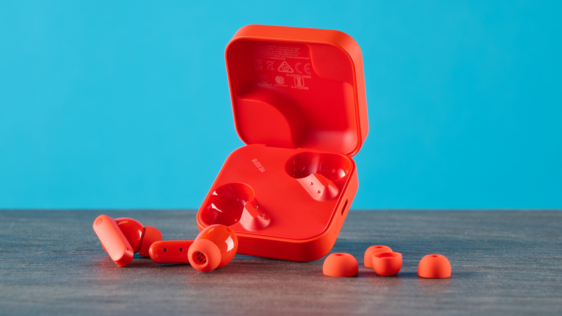 cmf buds 2a in the orange colorway photographed in front of a blue background