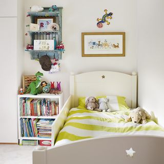 child bedroom with frame on wall and toys on bed