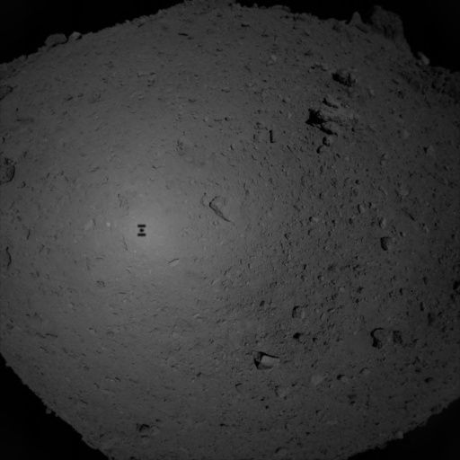 An image of the Hayabusa2 spacecraft silhouetted against Ryugu&#039;s surface, captured by the probe during its sampling procedure in February.