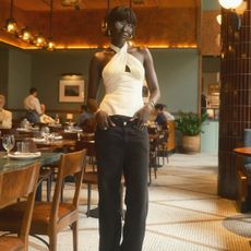 A woman wearing a white halterneck top with slim black pants 