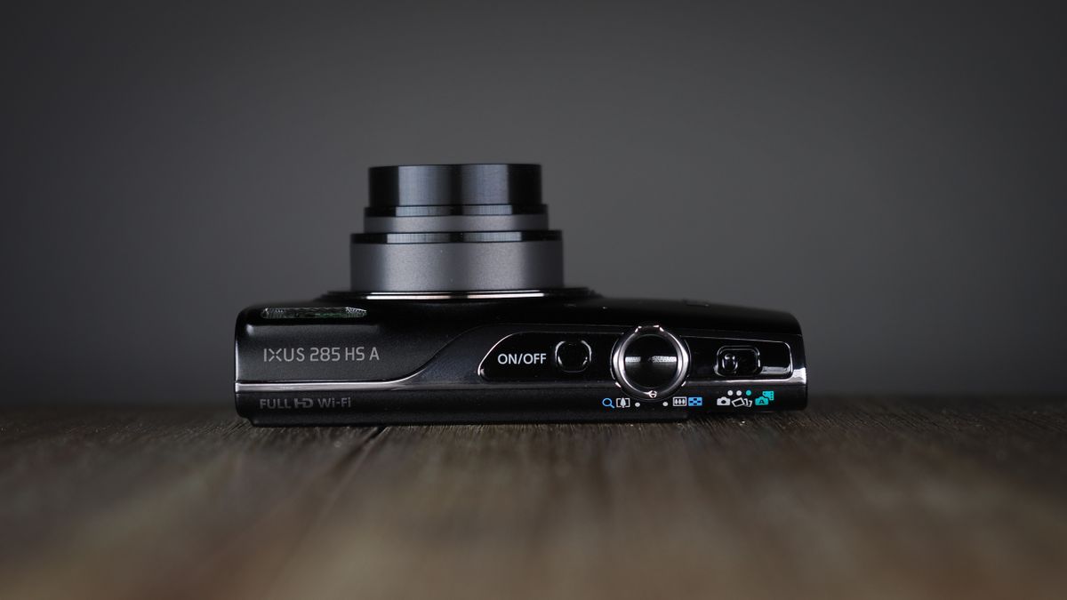 Canon Ixus 285 HS A on a wooden surface against a dark background