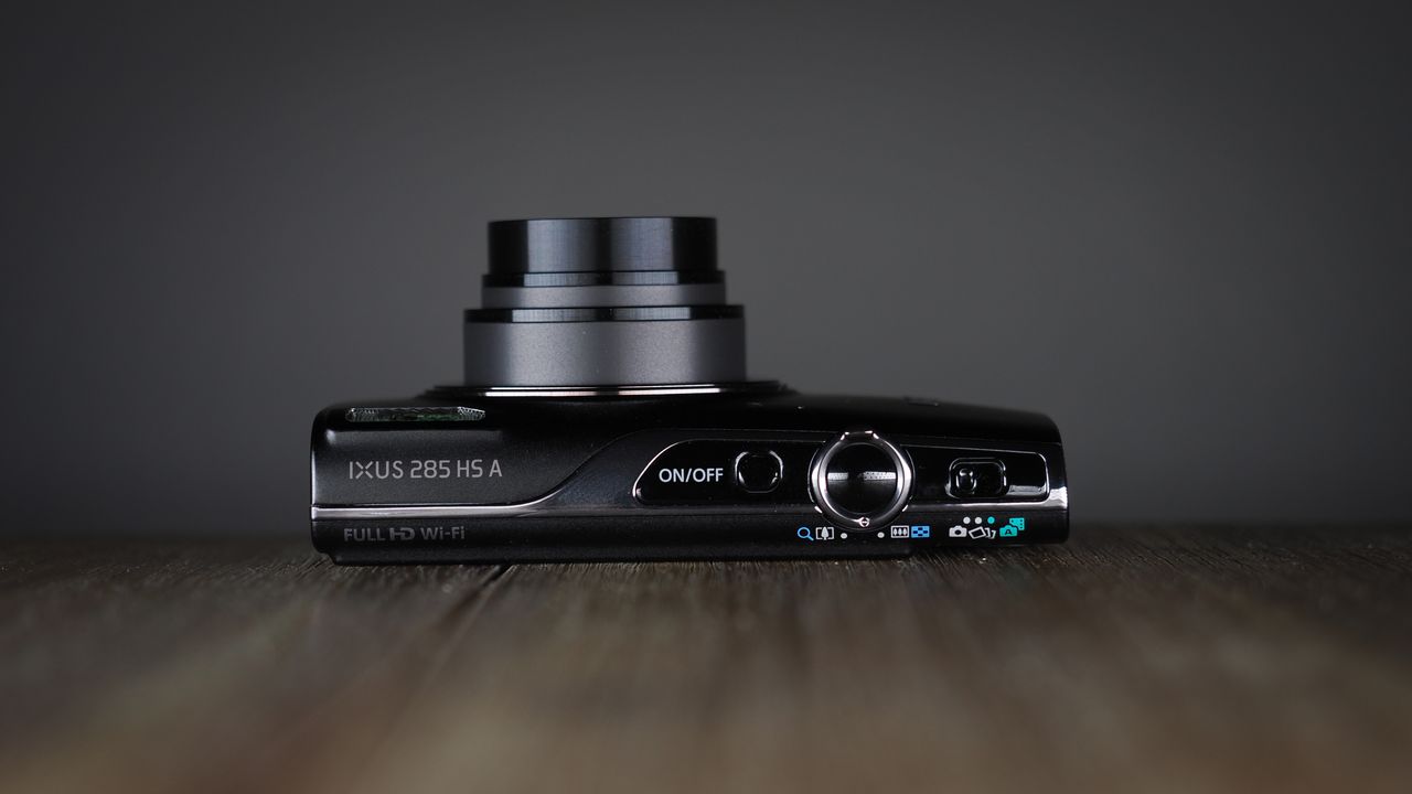 Canon Ixus 285 HS A on a wooden surface against a dark background