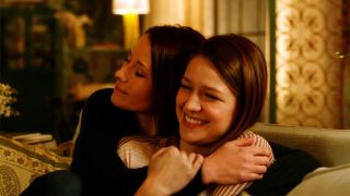 Melissa Benoist and Chyler Leigh hug on a couch in emotional Supergirl scene.