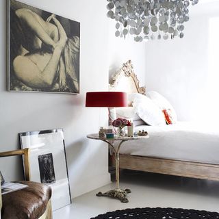 white bedroom with wall painting and red lamp