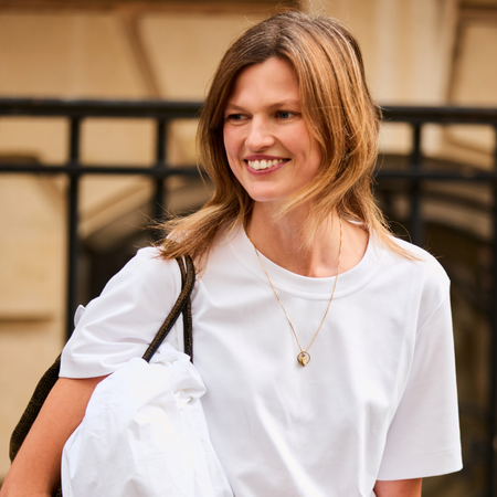 A smiling woman wears a basic white T-shirt. 