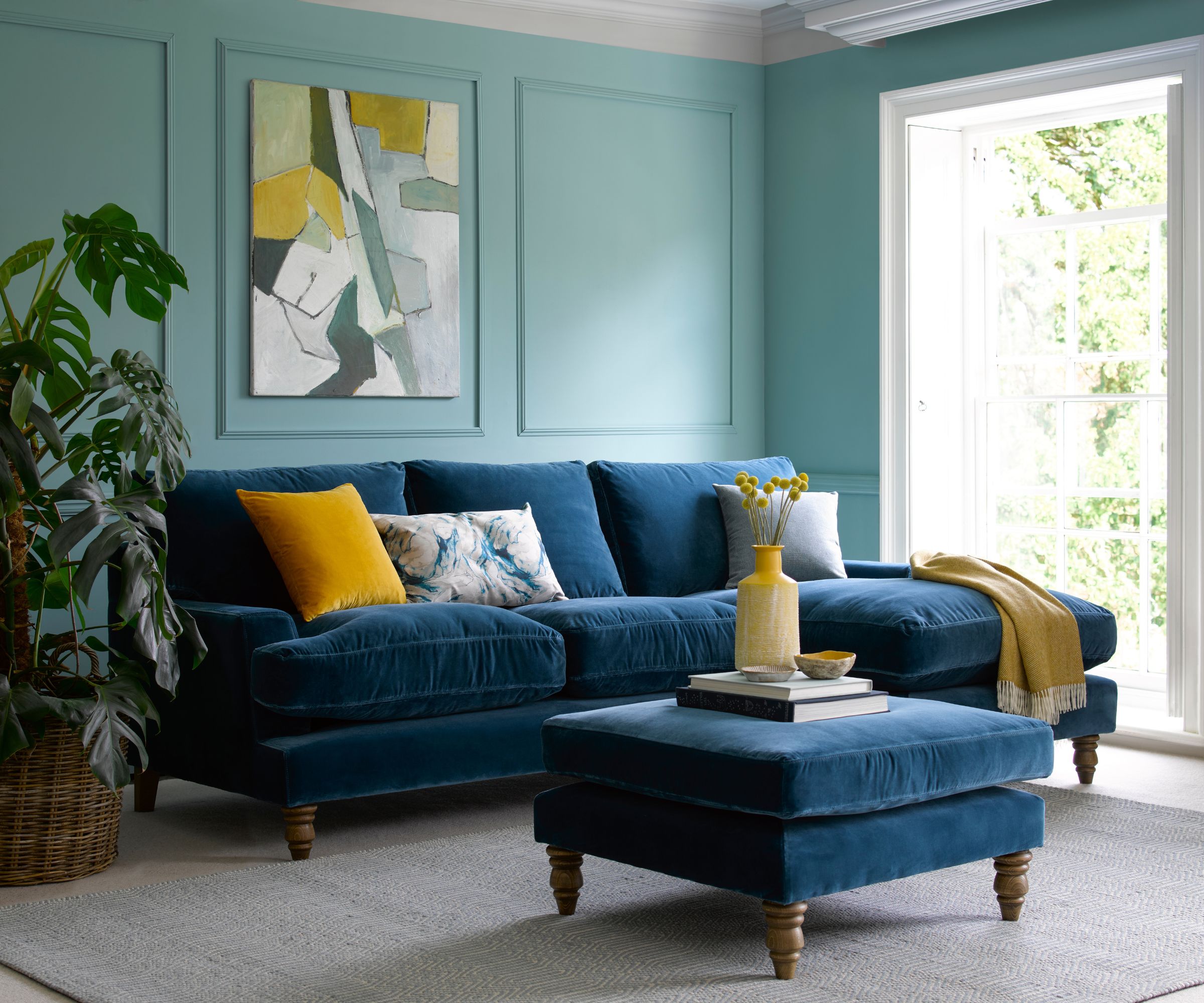 Living room with blue sofa and blue footstool in foreground