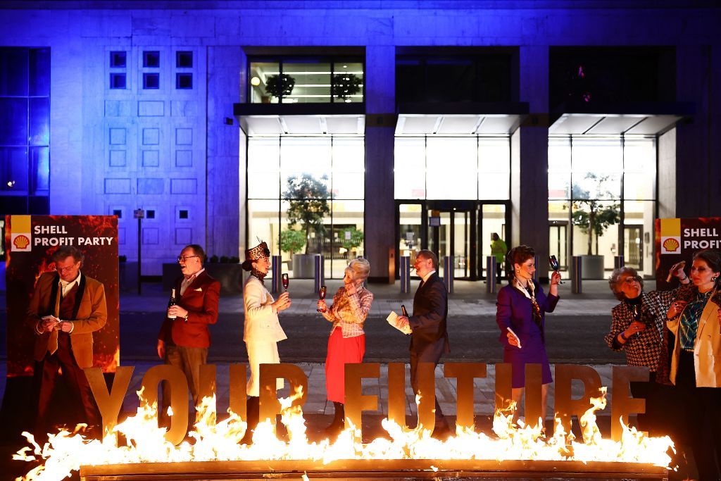 Greenpeace activists dressed as Shell board members hold a mock Shell profits party behind a burning sign reading &quot;Your Future&quot; during a protest outside Shell&#039;s headquarters in London on February 1, 2024, on the day that the oil and gas company releases its annual results